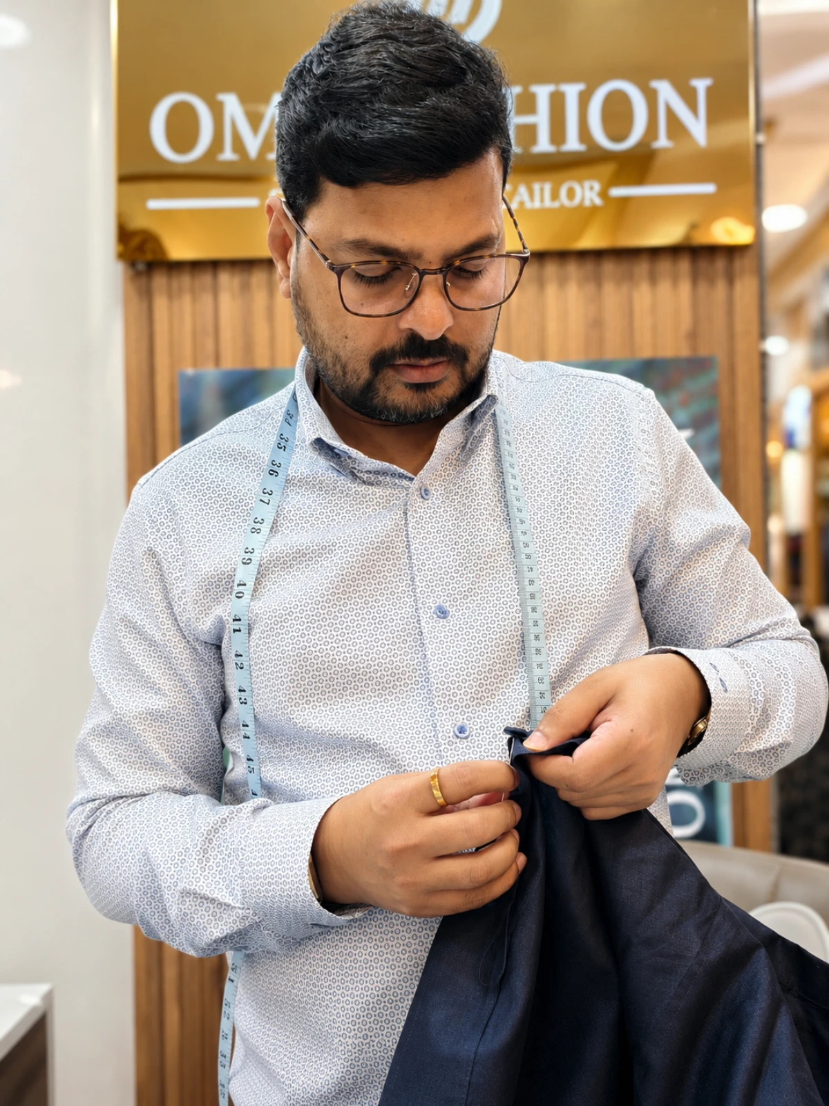 Tailor adjusting a jacket during an in-room hotel fitting on the Bangkok riverside