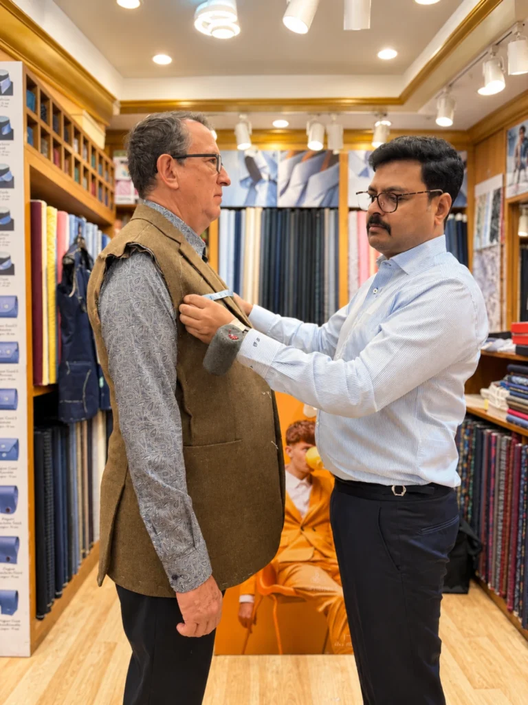 Om, master tailor in Bangkok, measuring a client at Om Fashion in Bang Rak